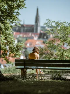Žena sedící na lavičce v parku během dne
