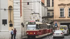 Červený a bílý vlak jedoucí podél ulice vedle vysokých budov