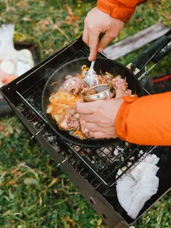 osoba griluje jídlo na venkovním grilu