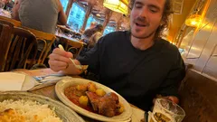 Muž si v restauraci pochutnává na jídle s masem a bramborami