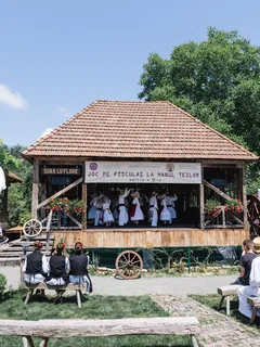 Lidé sedí na lavičce u dřevěné budovy během tradičního festivalu v Danesti