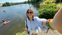 Žena dělá selfie u jezera za slunečného dne s plavci ve vodě