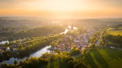 Letecký pohled na řeku a město při západu slunce s zelení kolem