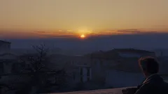 Muž sledující západ slunce nad městem za soumraku