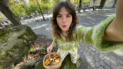 Žena v parku drží košík s houbami a fotí selfie, podzimní procházka přírodou.