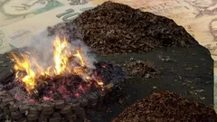 Hořící uhlí na hromadě s českými bankovkami v pozadí, symbol energetické krize